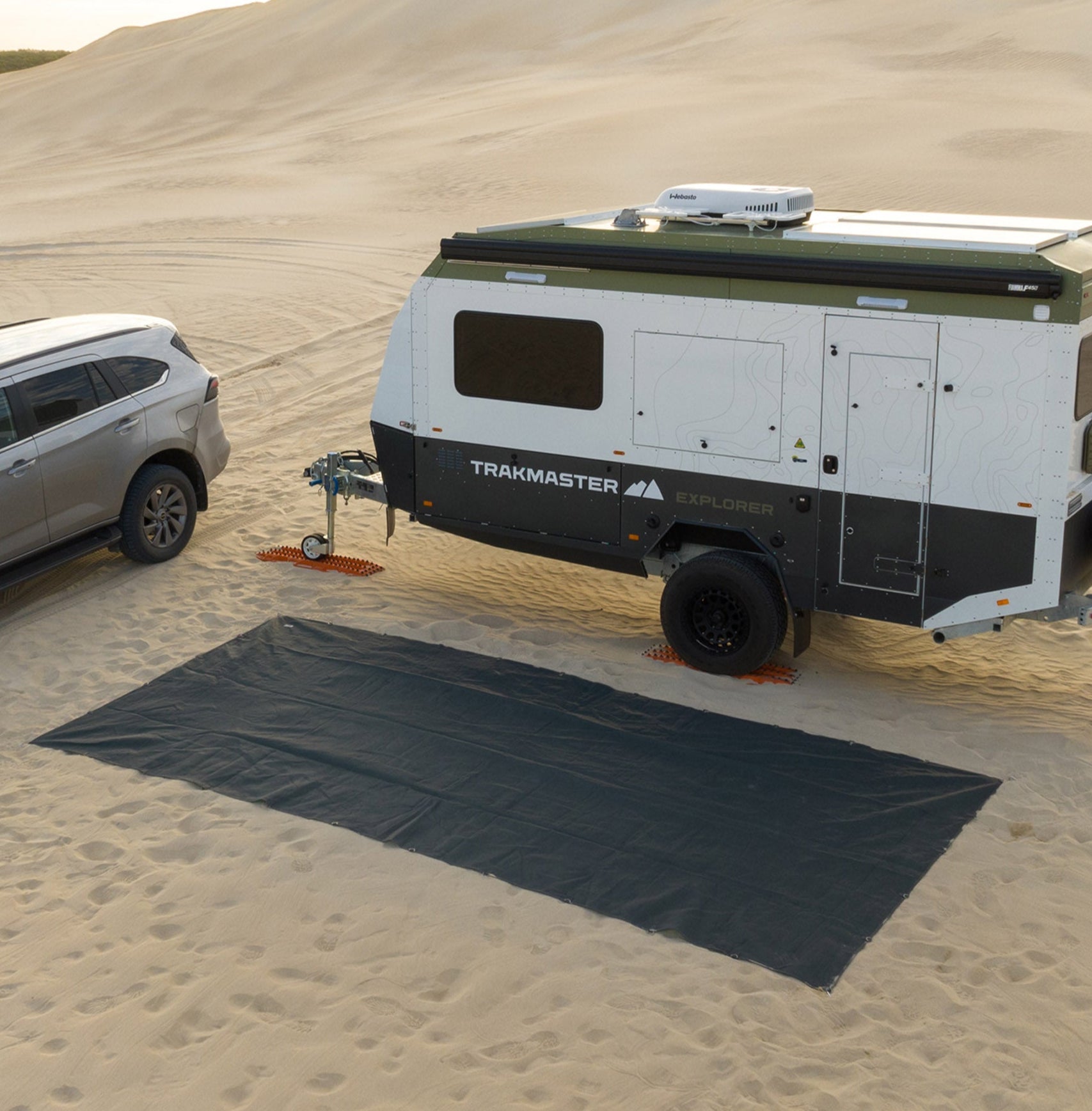 Camping setup with chairs, table, and a vehicle overlooking a scenic, green landscape.